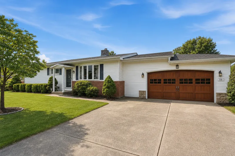 White ranch home with a wood-tone carriage garage door on a sunny day